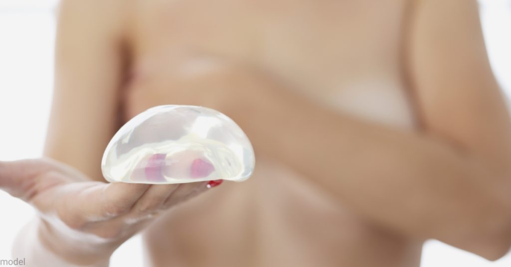 woman holding breasts and silicone breast implant (model)