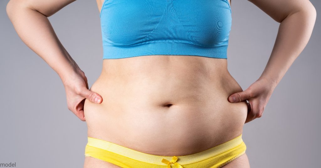 woman grabbing her side stomach fat and pulling it (model)